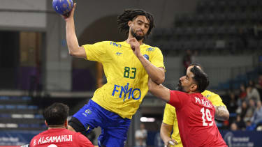TOPSHOT - Brazil's left wing #83 Hugo Bryan Monte da Silva jumps to shoot in spite of Bahrain's left wing #09 Hasan Alsamahiji and Bahrain's pivot #19 Mohamed Ali during the qualifying handball match for the 2024 Paris Olympic Games between Bahrain and Brazil at the Palau d'Esports in Granollers on March 15, 2024. (Photo by Josep LAGO / AFP) (Photo by JOSEP LAGO/AFP via Getty Images)